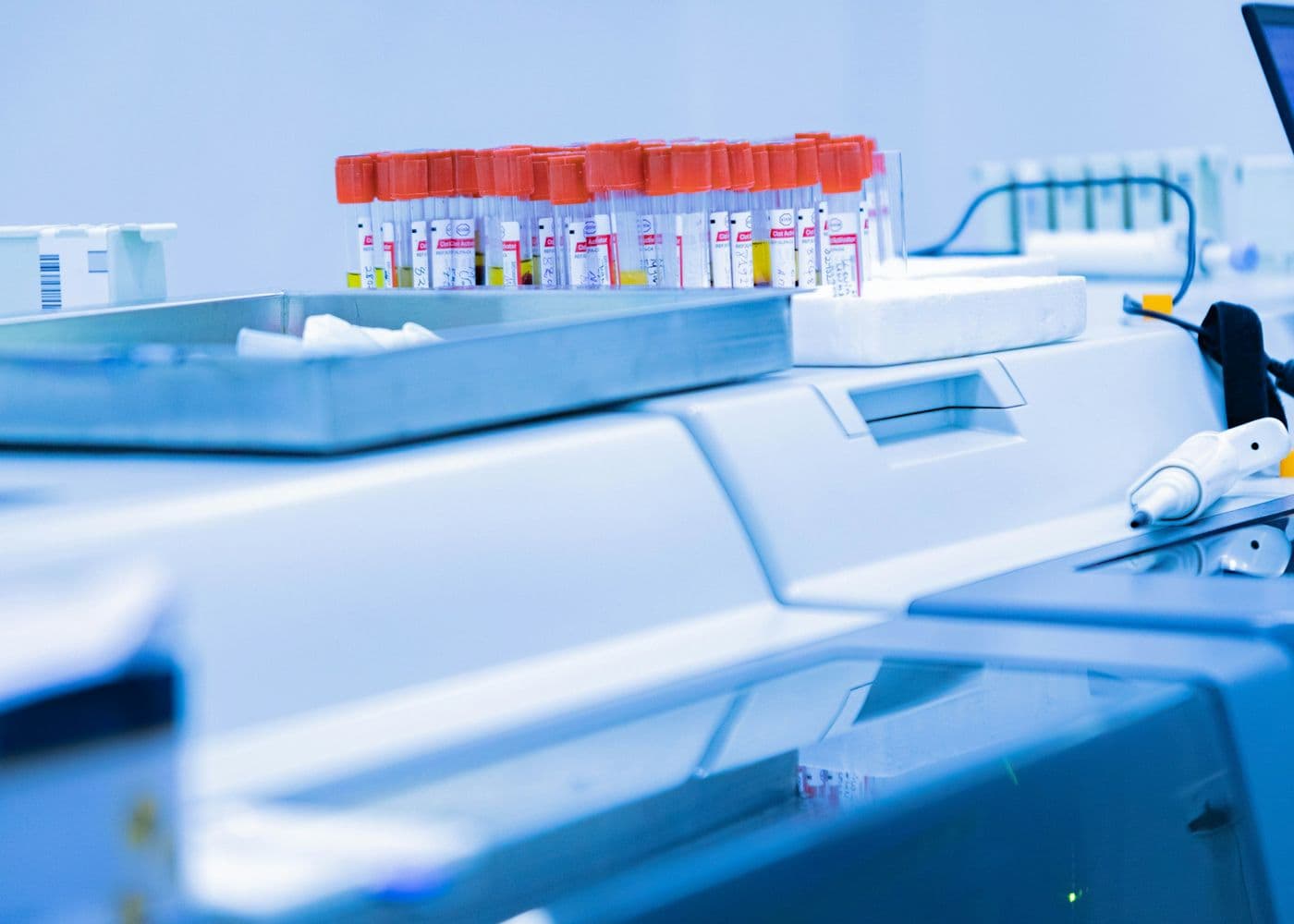 Rack of blood sample tubes on a blue-lit laboratory analyzer